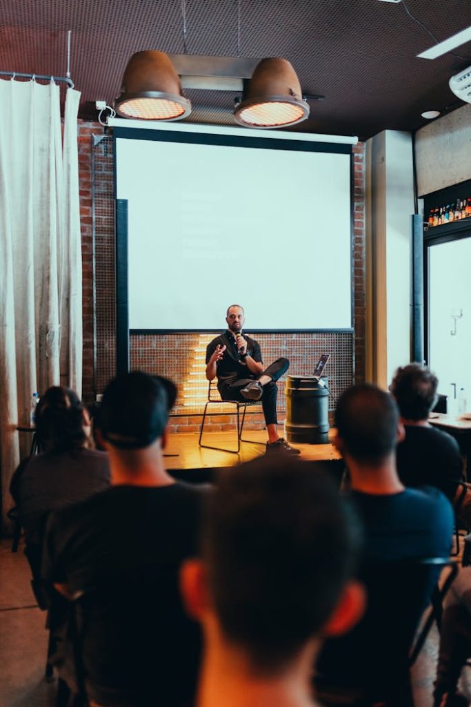 photo-of-man-sitting-in-front-3321796 Speaker engages an audience during a business seminar in a modern conference room.